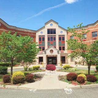 A modern educational institution surrounded by vibrant landscaping under a clear blue sky.