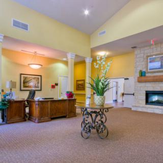 A spacious lobby area featuring a reception desk, decorative plants, and a cozy fireplace.