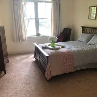 A cozy bedroom with a neatly made bed, decorated with a vase of flowers on a tray.