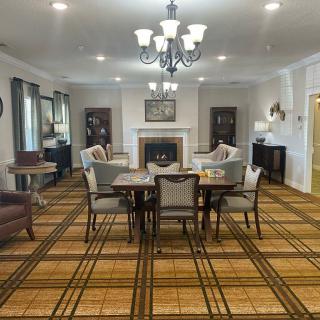 A well-furnished living room featuring a central table with chairs, a fireplace, and elegant lighting.