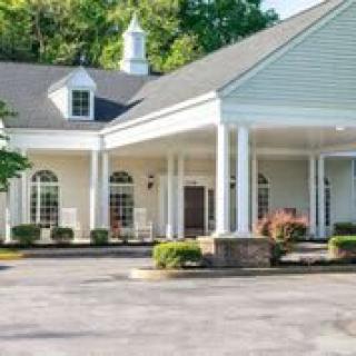 A building with a covered entrance featuring columns and surrounding landscaping.
