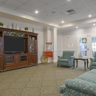 A cozy living room with armchairs, a large television, and tasteful decor.