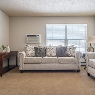 A cozy living room with a sofa and cushions by a window.