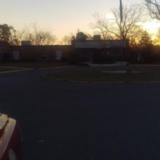 A serene view of a building at sunset, surrounded by trees.