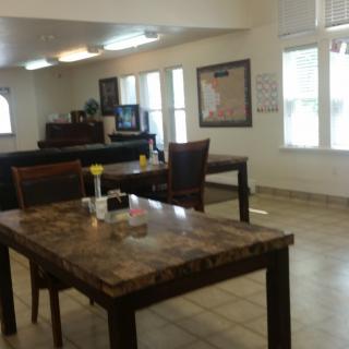 A spacious dining area with tables and chairs, featuring large windows that provide natural light.