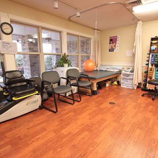 A bright and well-equipped physical therapy room with various rehabilitation tools and exercise equipment.