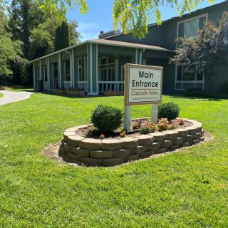 A building with a landscaped entrance featuring a sign for the main entrance of a clinic.