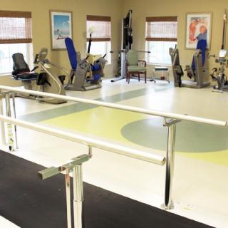 A physical therapy room equipped with exercise machines and parallel bars for rehabilitation exercises.