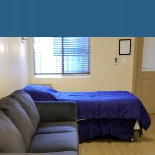 A simple room with a bed and a sofa next to a window.