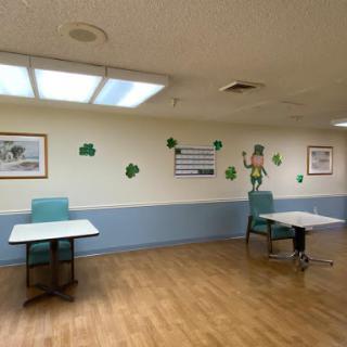 A spacious interior room featuring light-colored walls, wooden flooring, and simple furniture arrangement.
