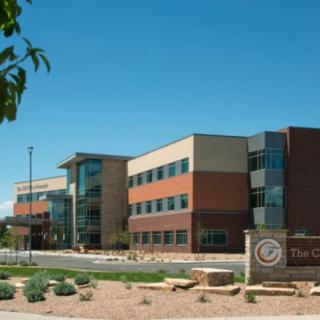 A modern office building with a landscaped entrance under a clear blue sky.