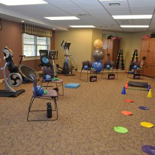 A fitness room equipped with various exercise tools, including balance balls, stationary bikes, chairs, and cones.