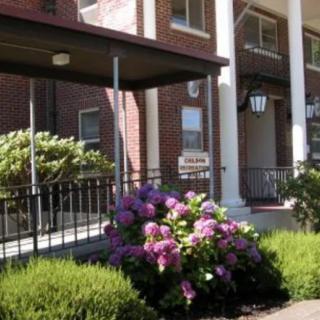 A building entrance with blooming flowers and large columns.
