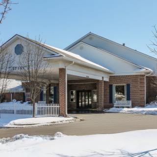 A winter scene featuring a building with a covered entrance, surrounded by snow.