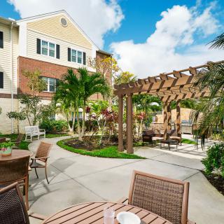 A beautifully landscaped outdoor patio area with seating and a pergola set against the backdrop of a residential building.