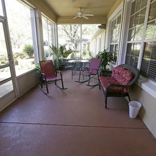 A cozy porch with seating, plants, and a ceiling fan.