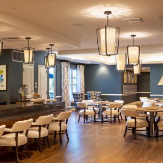 A well-lit restaurant interior featuring modern decor with neatly arranged tables and chairs.