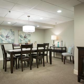 A well-lit dining room featuring a dark wooden table and chairs, with artwork on the walls and modern lighting.
