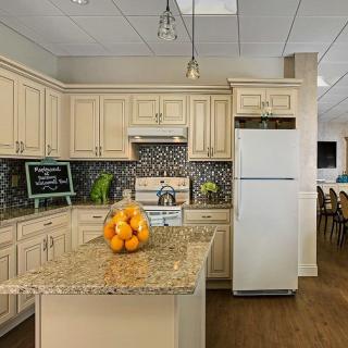 A modern kitchen with cream-colored cabinets and a granite countertop island, featuring a white refrigerator.