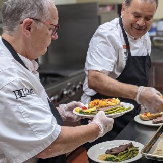 Chefs plating dishes in a restaurant kitchen.