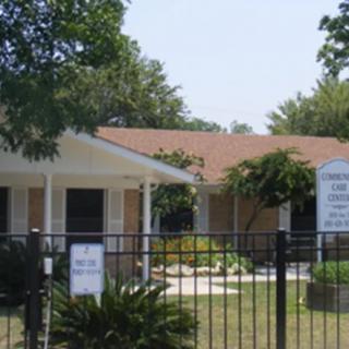 A house surrounded by a fence with a yard and trees.