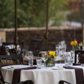 An elegantly set outdoor restaurant table adorned with flowers and glassware.