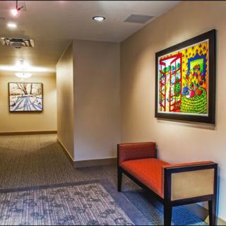 A modern hallway features colorful artwork and a red cushioned bench.
