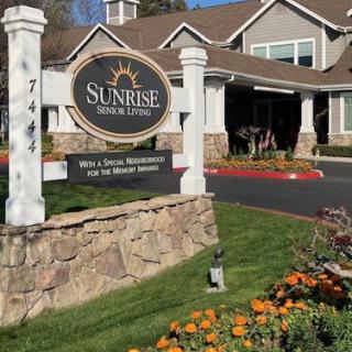 The entrance to a senior living community with landscaped gardens.