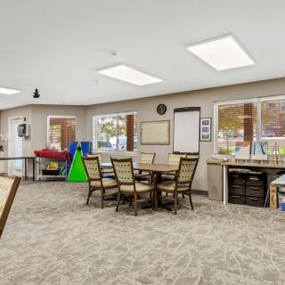 A spacious classroom with tables, chairs, and various art supplies.
