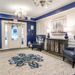 Elegant lobby with a blue and white color scheme, featuring comfortable seating, a chandelier, and decorative artwork.