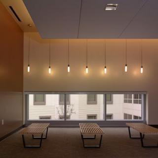 A modern interior space with hanging light fixtures and a seating area near large windows.