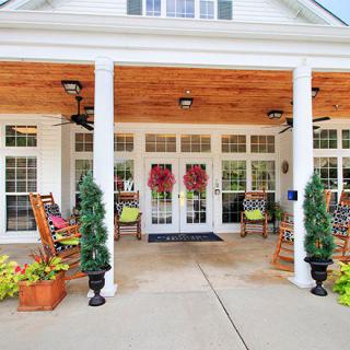 A welcoming porch with rocking chairs, wreaths on double doors, and decorative plants.