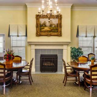 A cozy dining room featuring a fireplace, chandelier, and elegantly set tables.
