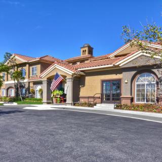 A residential building with an American flag displayed at the entrance under a clear blue sky.