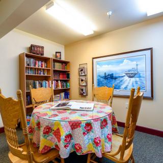 A cozy reading room with a round table and bookshelves.
