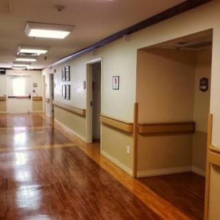 A clean and well-lit hallway with wooden floors and doorways on each side.