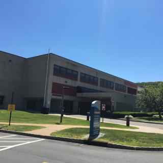 A modern building set in a grassy area on a bright, sunny day.