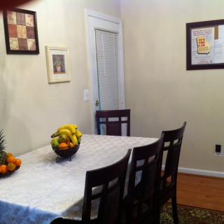 A cozy dining room with a table set with a fruit bowl and framed artwork on the walls.