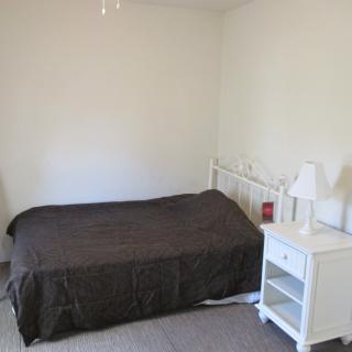 A minimalist bedroom with a bed and white nightstand.