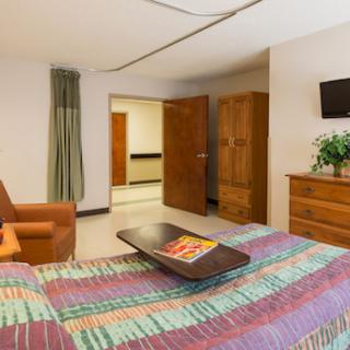 A cozy hotel room featuring a bed, couch, and wooden furniture, complete with a TV.