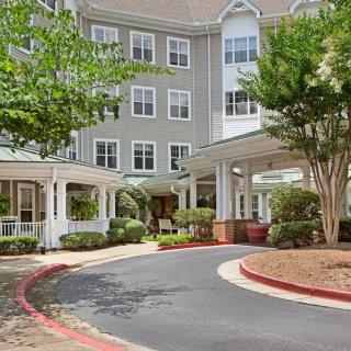 A well-maintained residential building with a driveway and surrounding greenery.