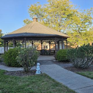 A charming gazebo surrounded by lush greenery in a peaceful park setting.