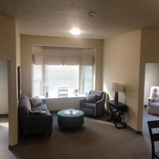 A cozy living room featuring a sofa, two chairs, and a coffee table in front of a large window.