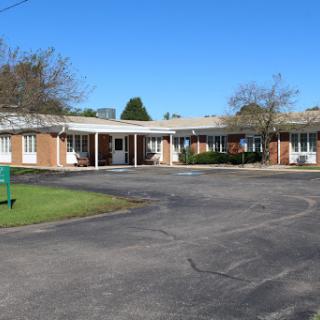 A view of a quaint motel featuring brick exterior and well-maintained landscaping under a clear blue sky.