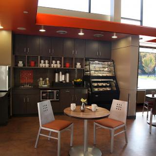 A cozy and modern caf space featuring a kitchenette with ample seating, highlighted by natural light.