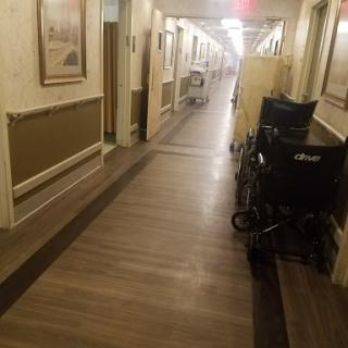 A quiet hallway in a healthcare facility, featuring wheelchairs alongside the walls.