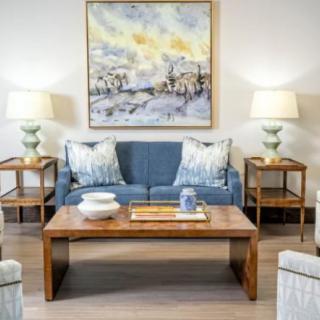 A cozy living room with a blue sofa, wooden coffee table, and decorative artwork on the wall.