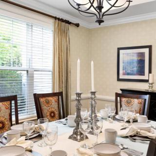 A beautifully set dining table with elegant candlesticks and a chandelier overhead.