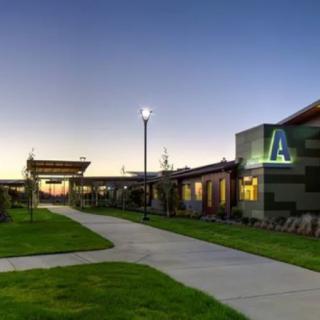 A modern building with a well-lit pathway and neatly maintained lawns during evening time.