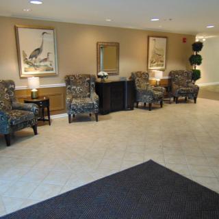A well-furnished lobby with upholstered chairs, artwork, and a decorative mirror.